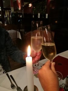Photo of friends toasting the book over restaurant table, celebrating the memoir's publication, In Germany.